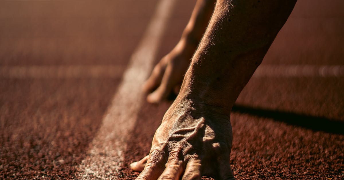 Close-up of an athlete's hands on a race track in Andenne, Belgium, ready for competition.